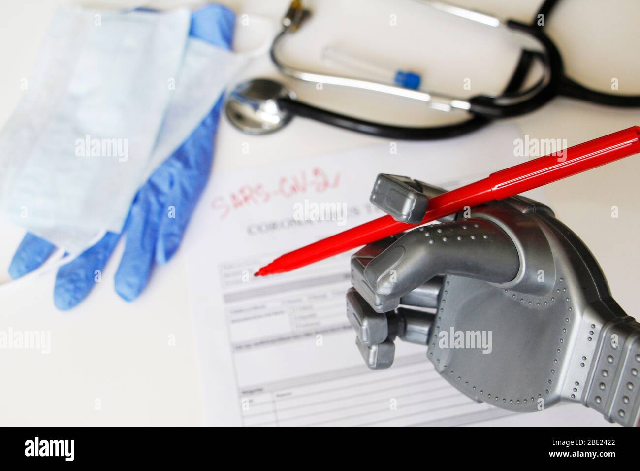 The robot writes SARS-SoV-2. Coronavirus test concept. Robotic medicine concept. On the table are a mask, latex gloves and a stethoscope. Stock Photo