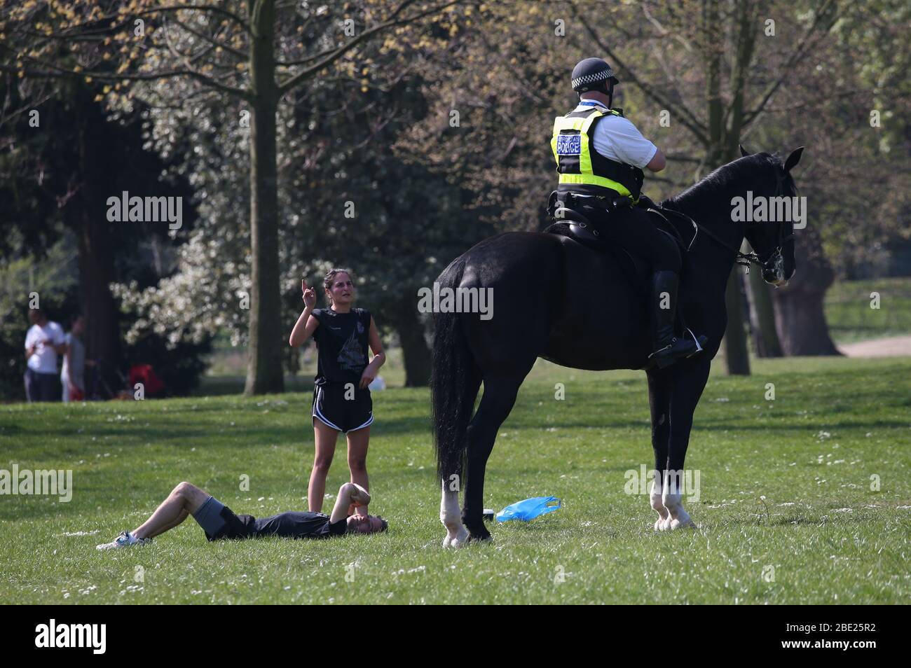 A mounted police officer offers advice to people using Victoria Park, in east London, after it was reopened with reduced opening hours and new control measures in place during the coronavirus outbreak. Stock Photo