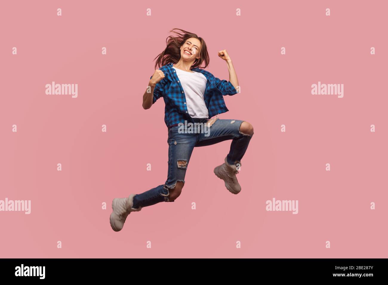 Full length of overjoyed ecstatic stylish girl jumping in air, gesturing i did it, celebrating success, flying and rejoicing her dream achievement. in Stock Photo