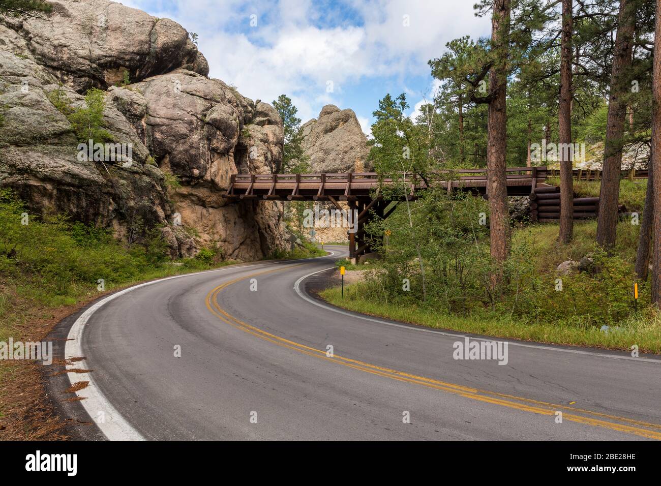 A road with an over and under bridge with a tunnel through a rock. Stock Photo