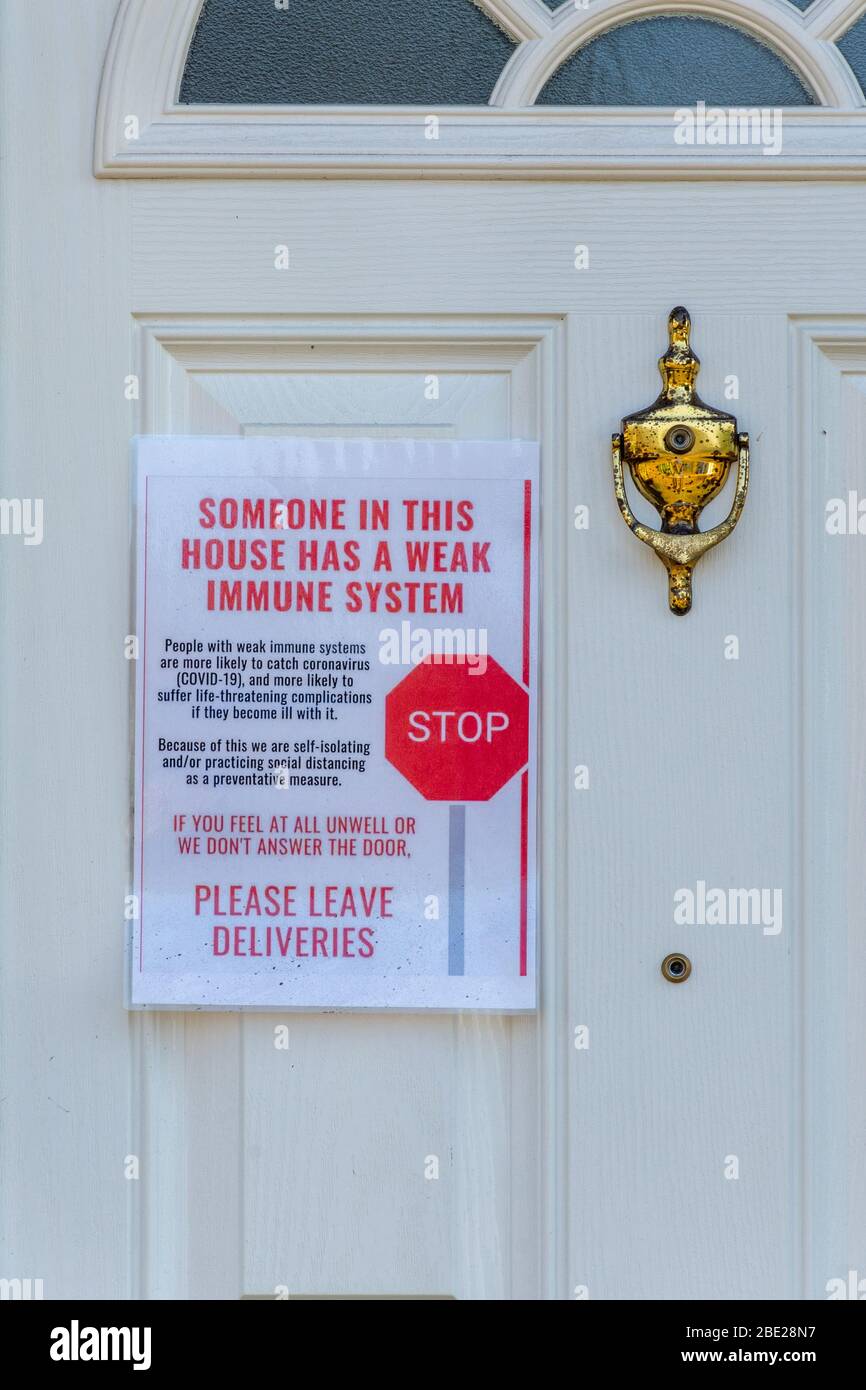10 April 2020. During the 2020 coronavirus Covid-19 pandemic, special care is being taken to protect vulnerable people and to prevent infection. This house has a notice on the front door stating that Someone in this house has a weak immune system. Stop. Please leave deliveries. Stock Photo