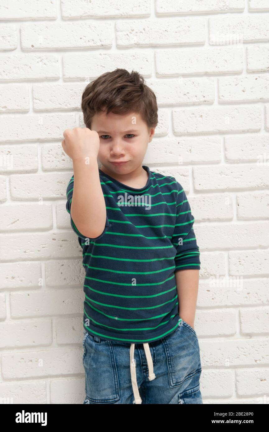 An angry frowning boy threatens with his fist Stock Photo