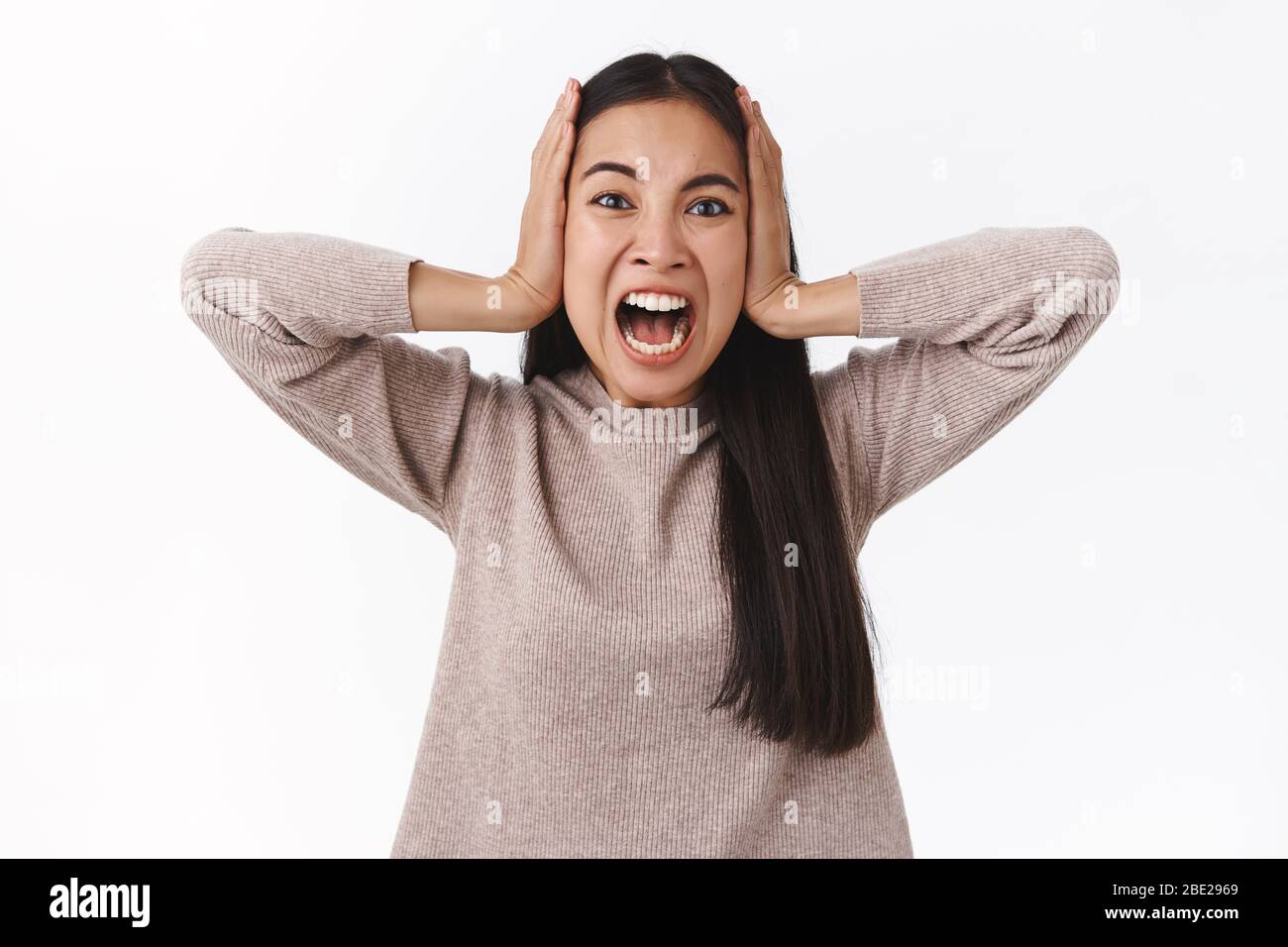 Distressed and fed up, depressed alarmed furious woman, losing control, having mental breakdown, shouting grab head and stare camera with pain and Stock Photo