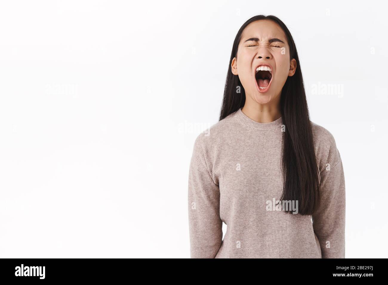 Fed up, outraged silly east-asian troubled teenager screaming bothered, being arrogant, shouting out loud with opened wide mouth, close eyes, whining Stock Photo