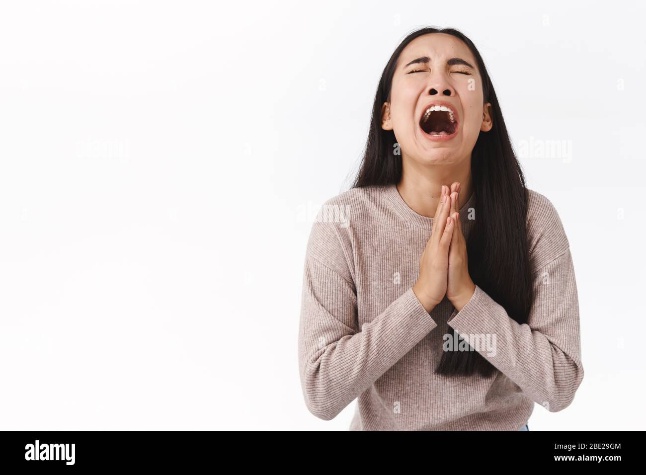 Girl crying her heart out begging for mercy or apology, telling she sorry, holding hands in pray