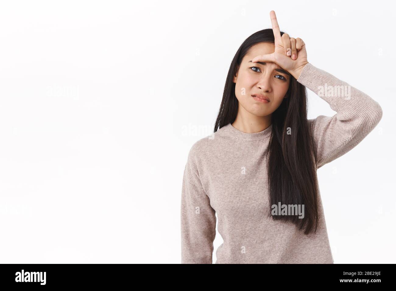 Waist-up shot distressed cute asian girl feeling down in dumps, upset with losing, showing L lette ron forehead as disgrace herself and feeling like Stock Photo