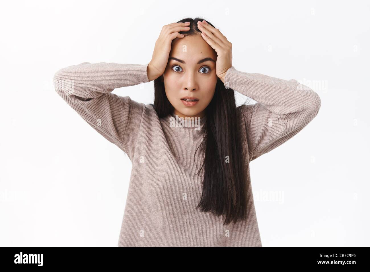 Annoyed and pressured, distressed fed up asian girlfriend tired constantly saying same things, grab head bothered, stare camera intense, losing temper Stock Photo