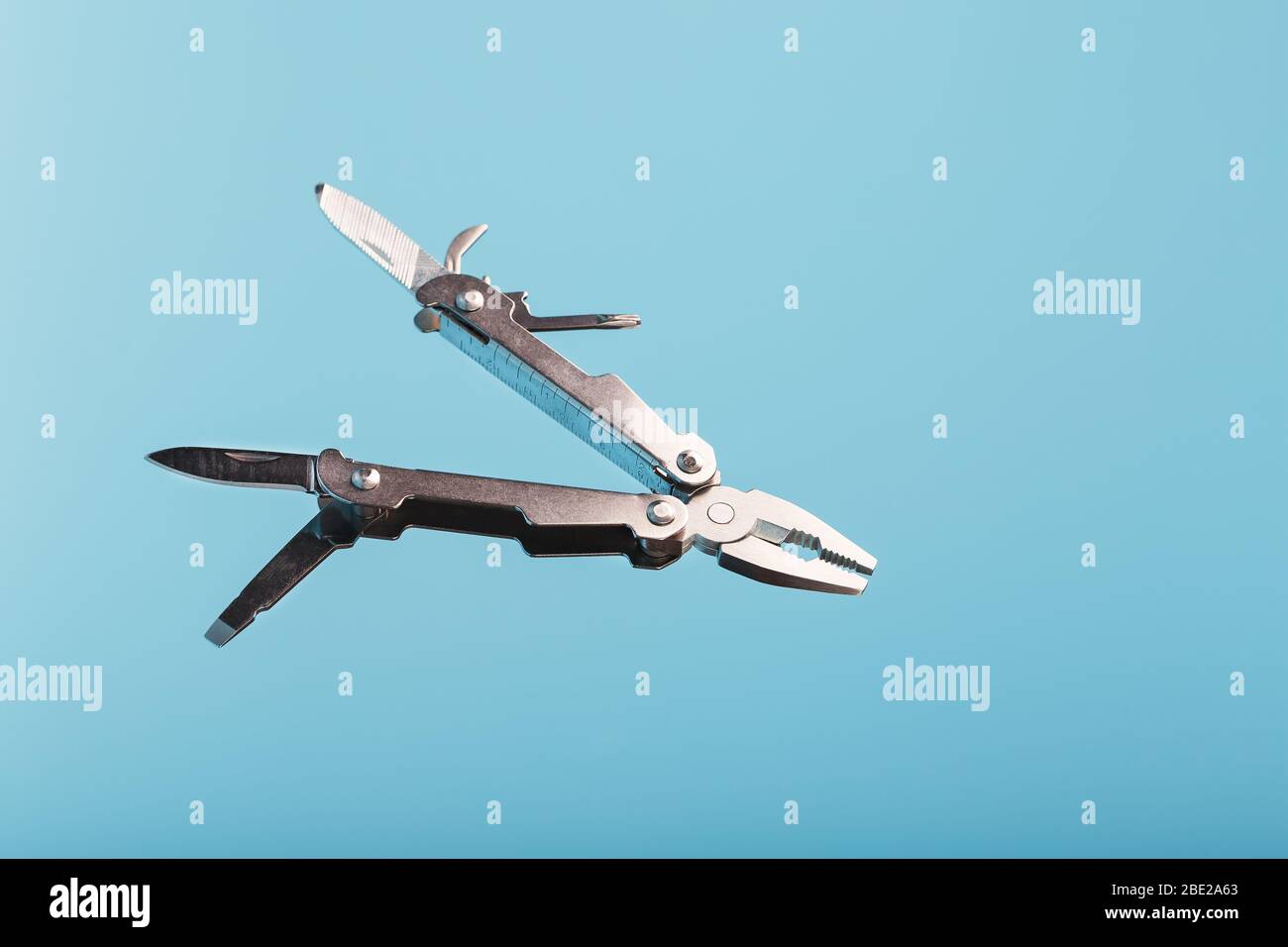 The multitool multi-function tool hovers on a blue background. The concept of an expanded multi-tool with free space. Stock Photo