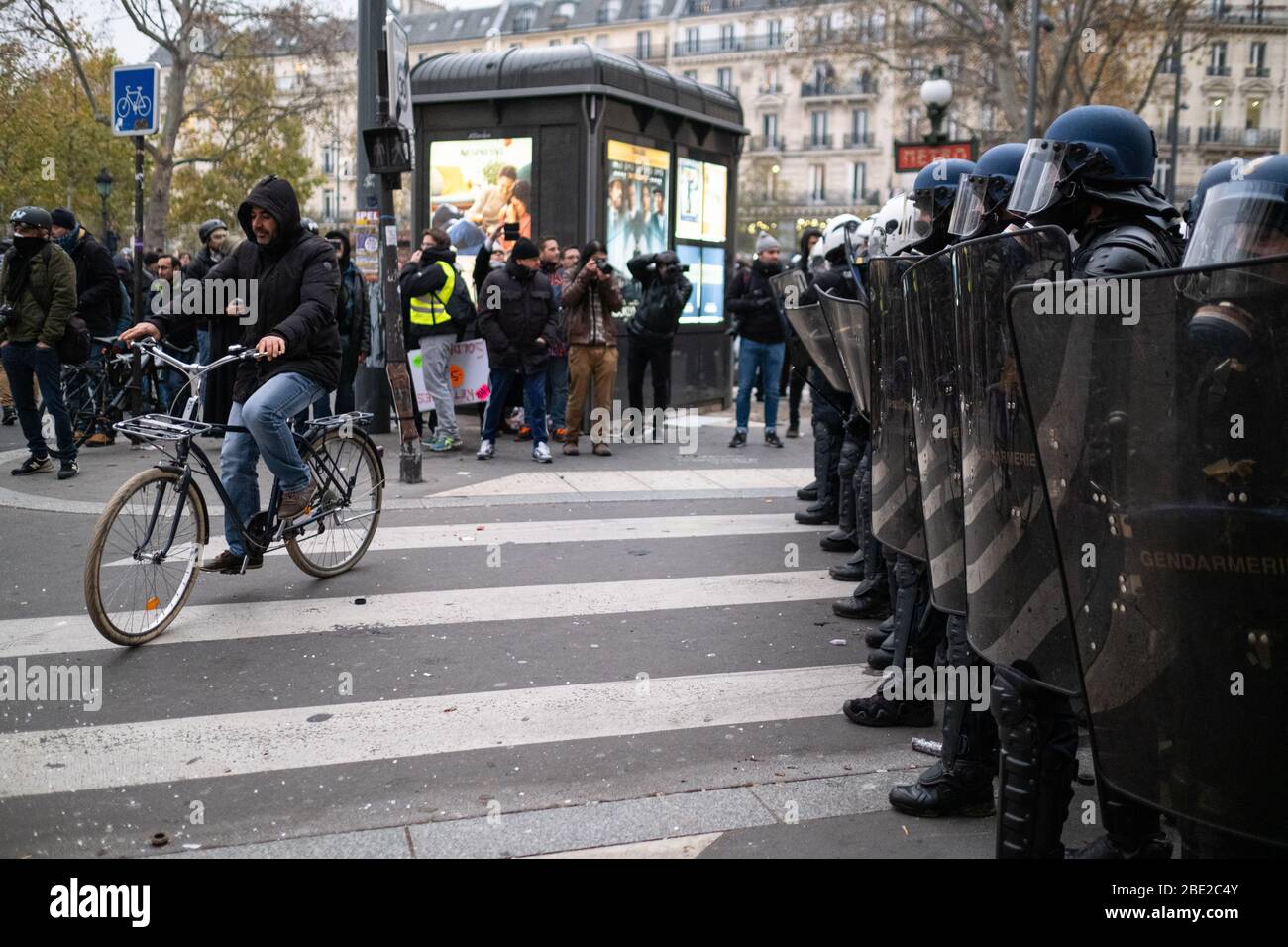 A cyclist passes a wall of police shields during the Paris General Strike. Stock Photo