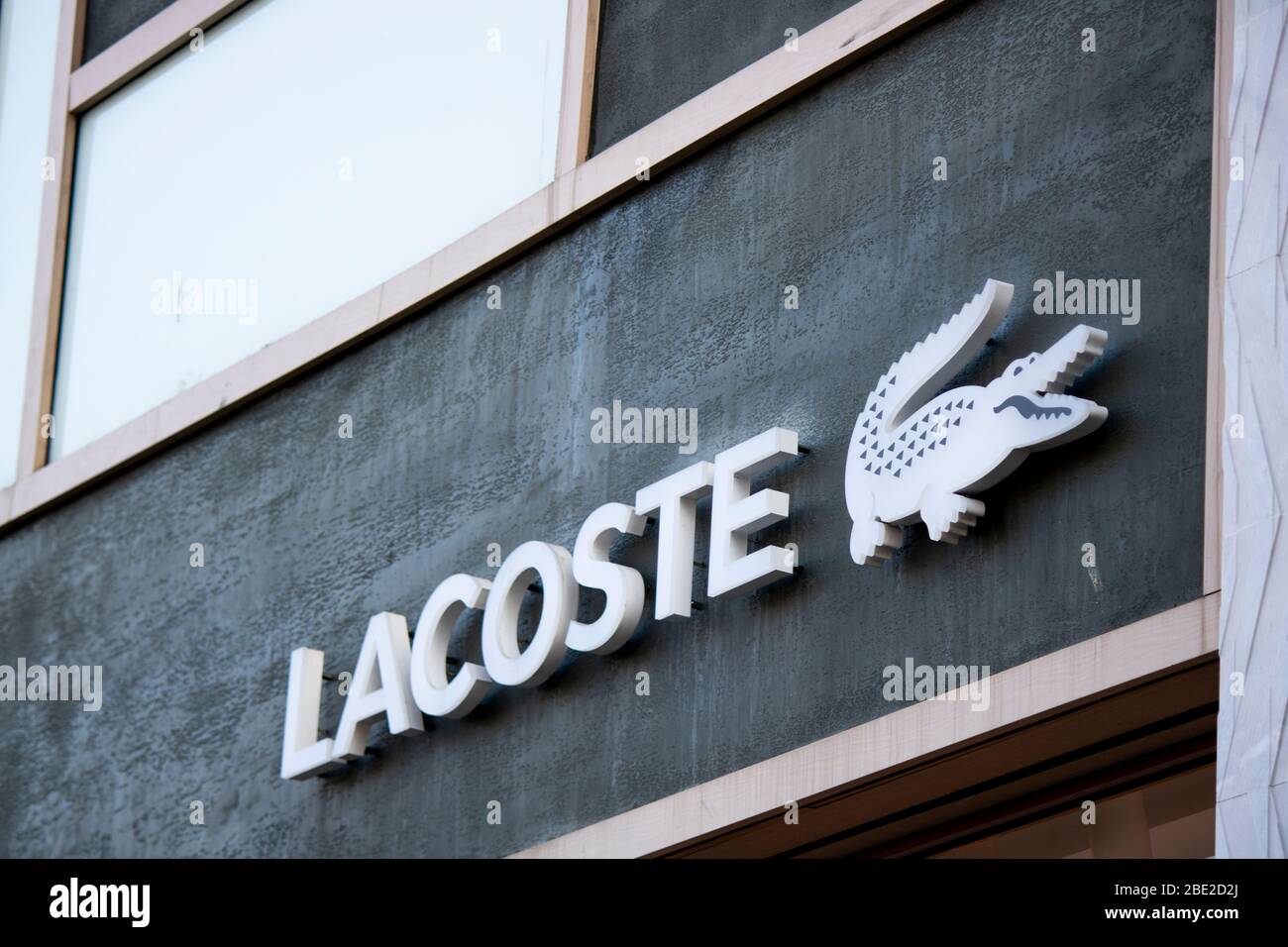 Lacoste brand white text on black wall. There is a crocodile mark on the  side Stock Photo - Alamy