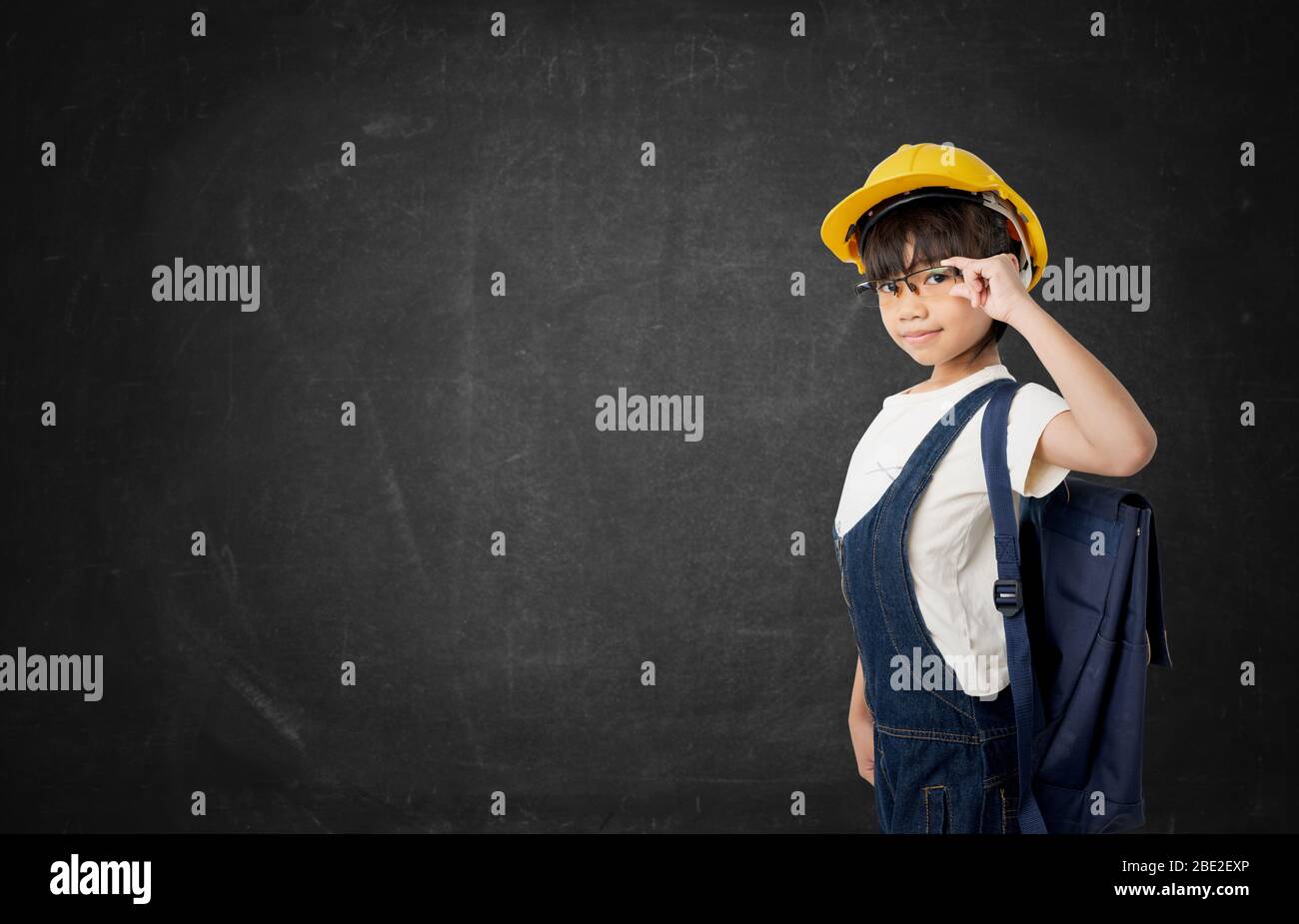 Asian girl Thai student want to be engineer, engineering kid isolated on dark chalkboard background Stock Photo
