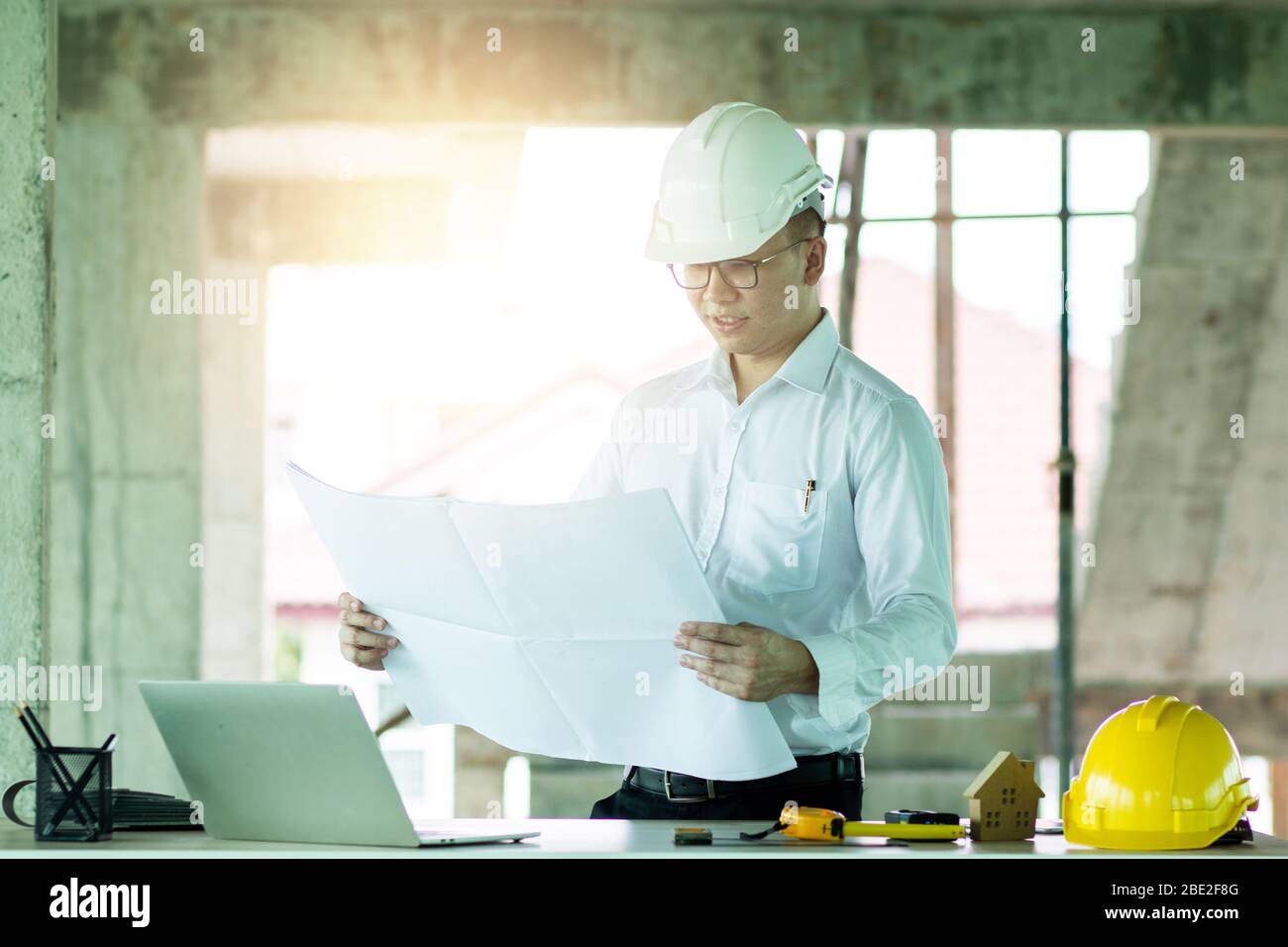 Smart engineer looking on blue print and checking job progress in