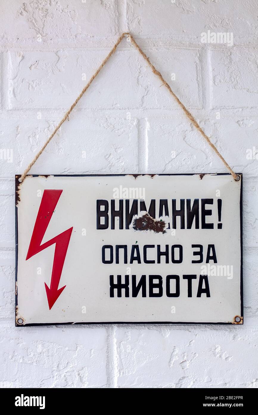 An old rusty enamelled Cyrillic sign warning of danger from an Eastern European country. Stock Photo