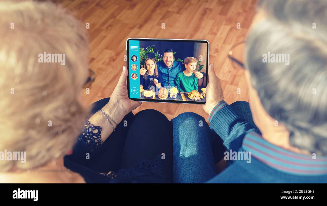Senior couple chatting on video call with son and grandchildren due to home isolation quarantine Stock Photo