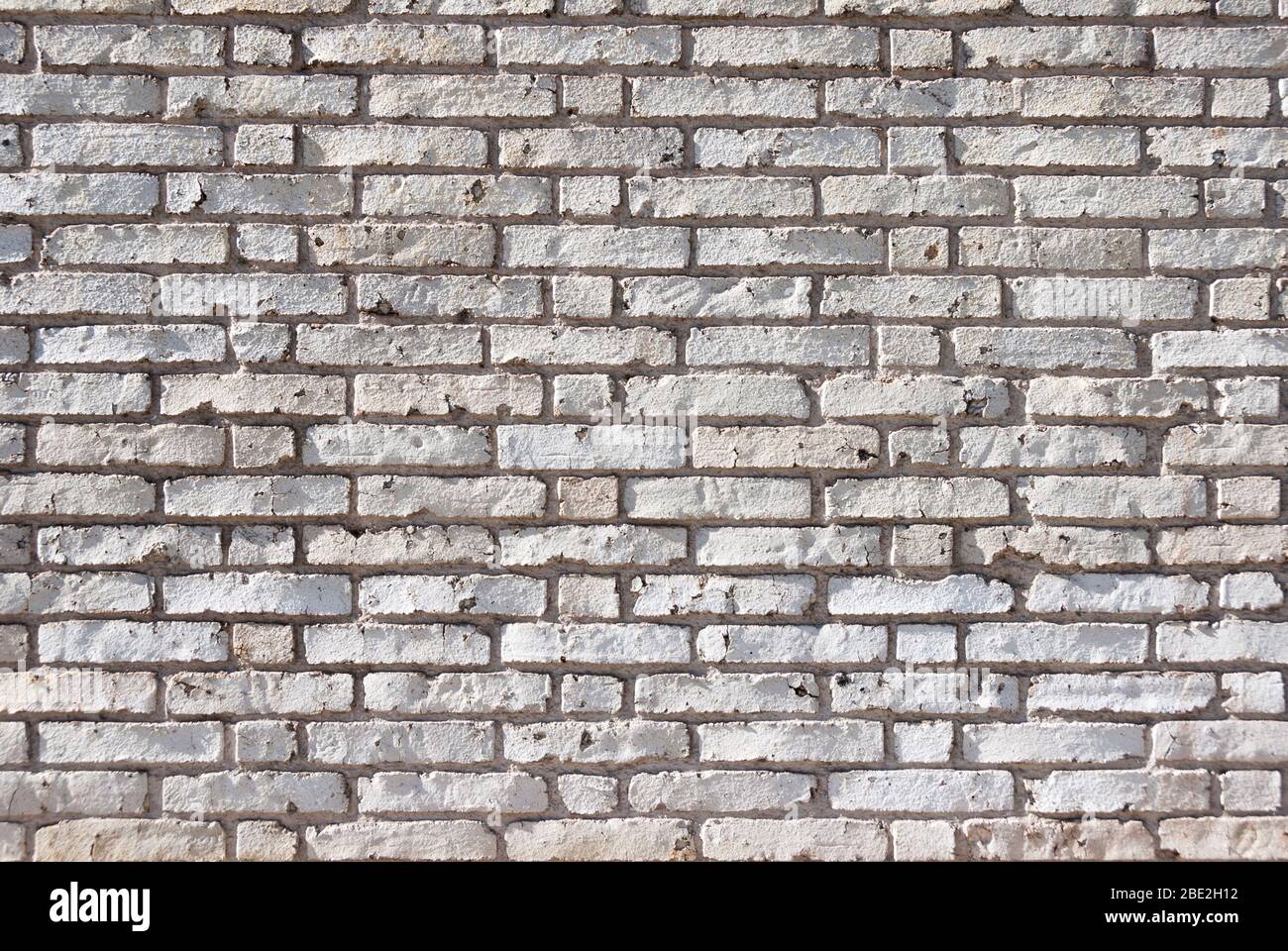 Full frame textured background of weathered brick wall with chipped and peeling white paint Stock Photo