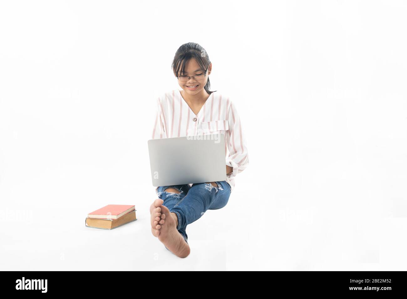 Young girl sitting and using laptop isolated on white background Stock ...