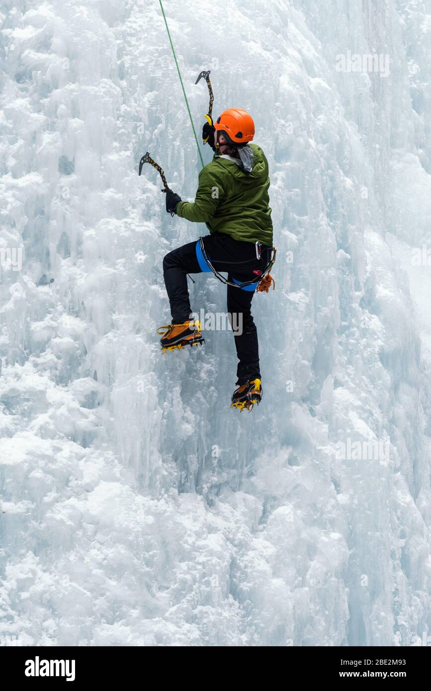 Ice climber using ice picks and crampons to climb a frozen waterfall in the Maligne Canyon, Jasper National Park, Alberta, Canada Stock Photo