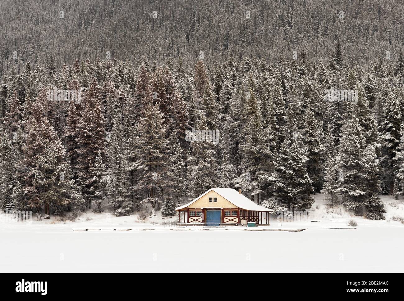 Frozen and snow covered Maligne lake with the Maligne Lake Boat House in front of a snow covered pine forest, Jasper National Park, Alberta, Canada Stock Photo