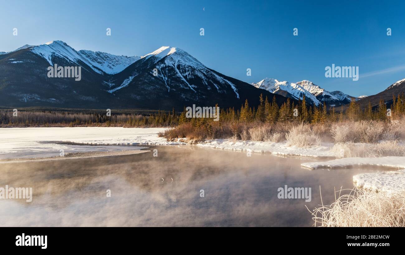 Snow capped Sundance Peak and fir trees reflected in the still waters of Vermillion Lakes, Banff National Park, Banff, Alberta, Canada Stock Photo