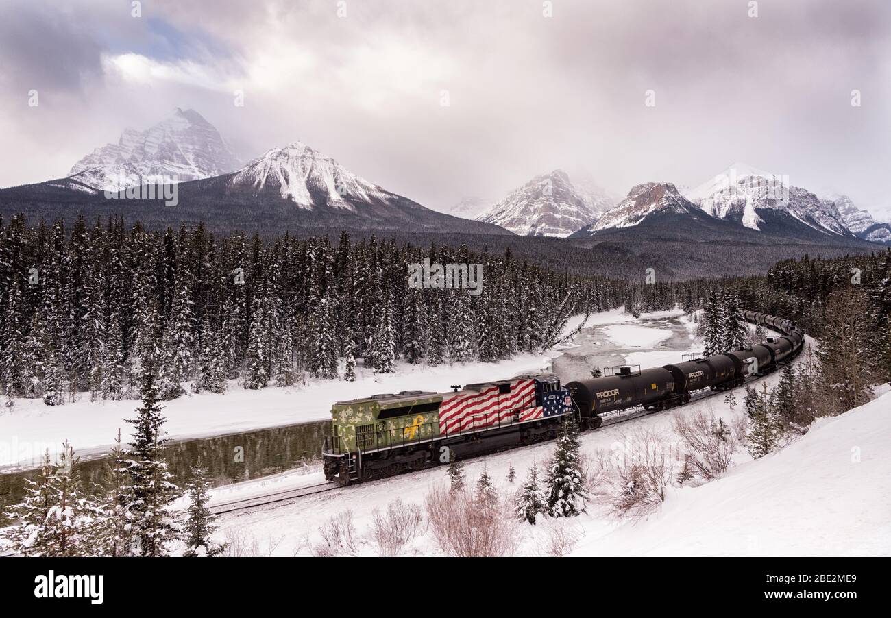 A Canadian Pacific freight train at Morant's Curve in winter along the Bow River on the Bow Valley Parkway near Banff, Alberta, Canada Stock Photo