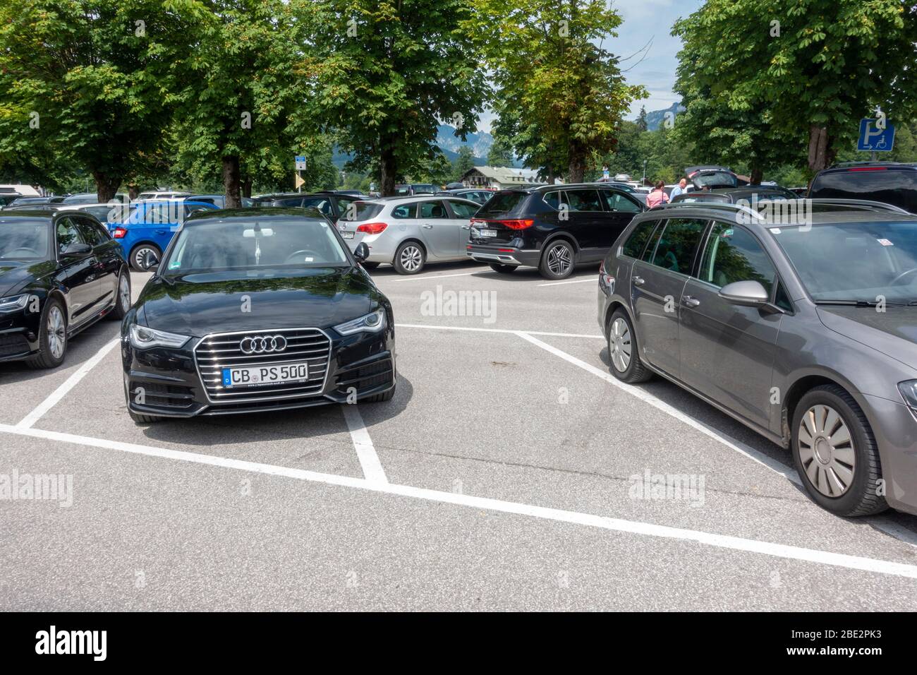 An example of either poor/bad/selfish parking or too thin parking bays in a packed car park in Konigssee, Bavaria, Germany. Stock Photo