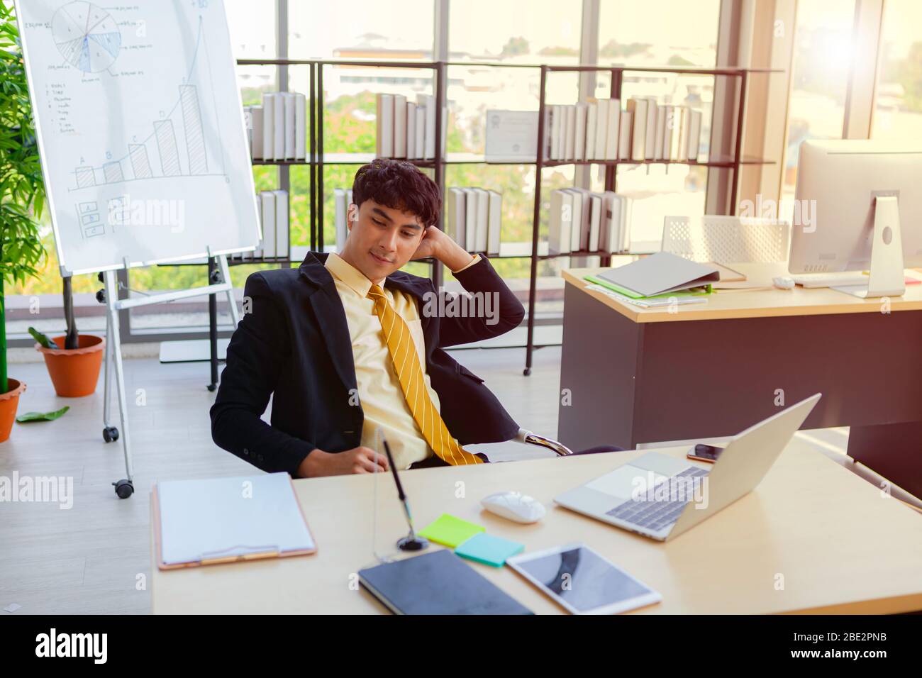 A young businessman is sitting down for a short break from hard work throughout his work hours to relieve stress and create new ideas from working in Stock Photo