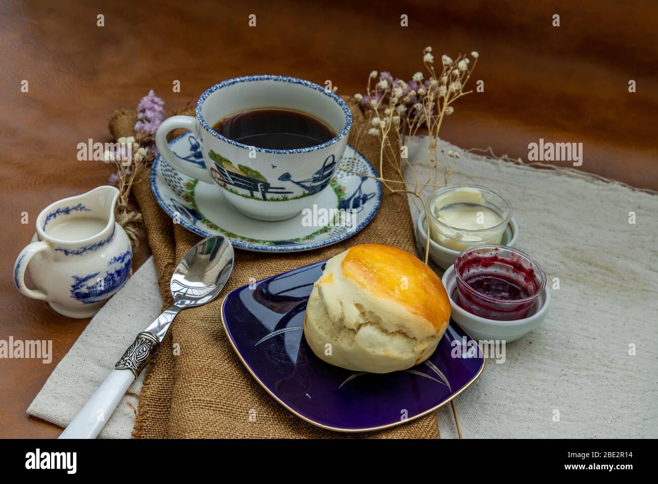 Scones with mascarpone cheese and raspberry jam served with black coffee with milk on sack cloth for new morning. Selective focuse. Stock Photo
