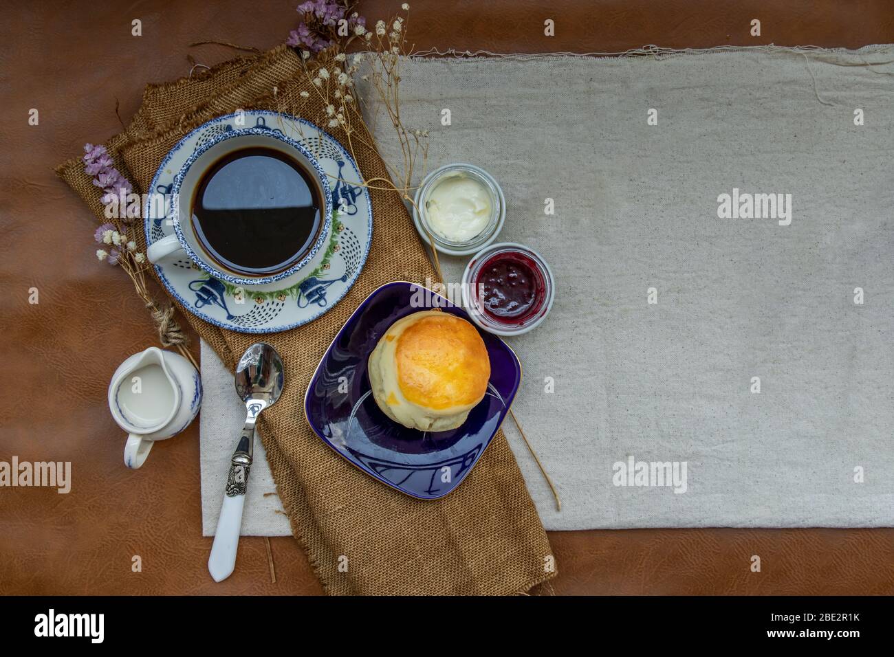 Scones with mascarpone cheese and raspberry jam served with black coffee with milk on sack cloth for new morning. Selective focuse. Stock Photo