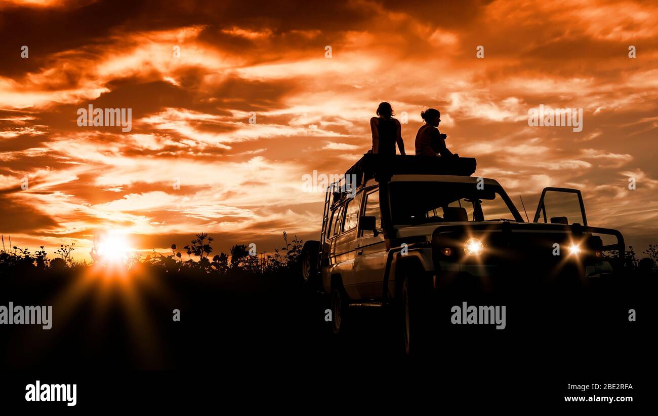 Zwei Frauen, die auf ihren Jeep sitzen und den Sonnenuntergang ueber dem Outback in Australien bewundern Stock Photo