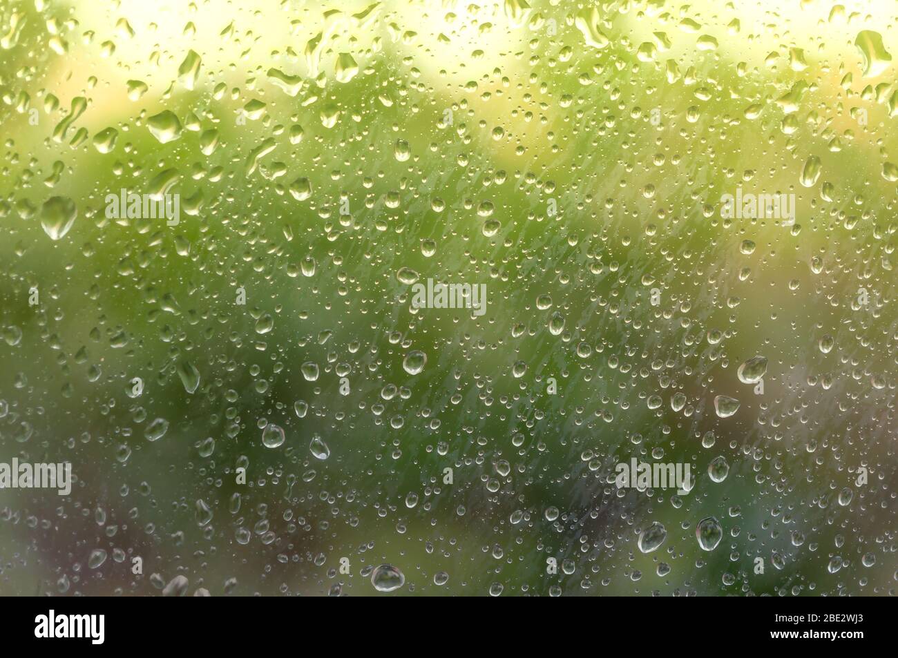 Raindrops on fogged glass are illuminated by the first rays of the sun after bad weather. Soft focus Stock Photo