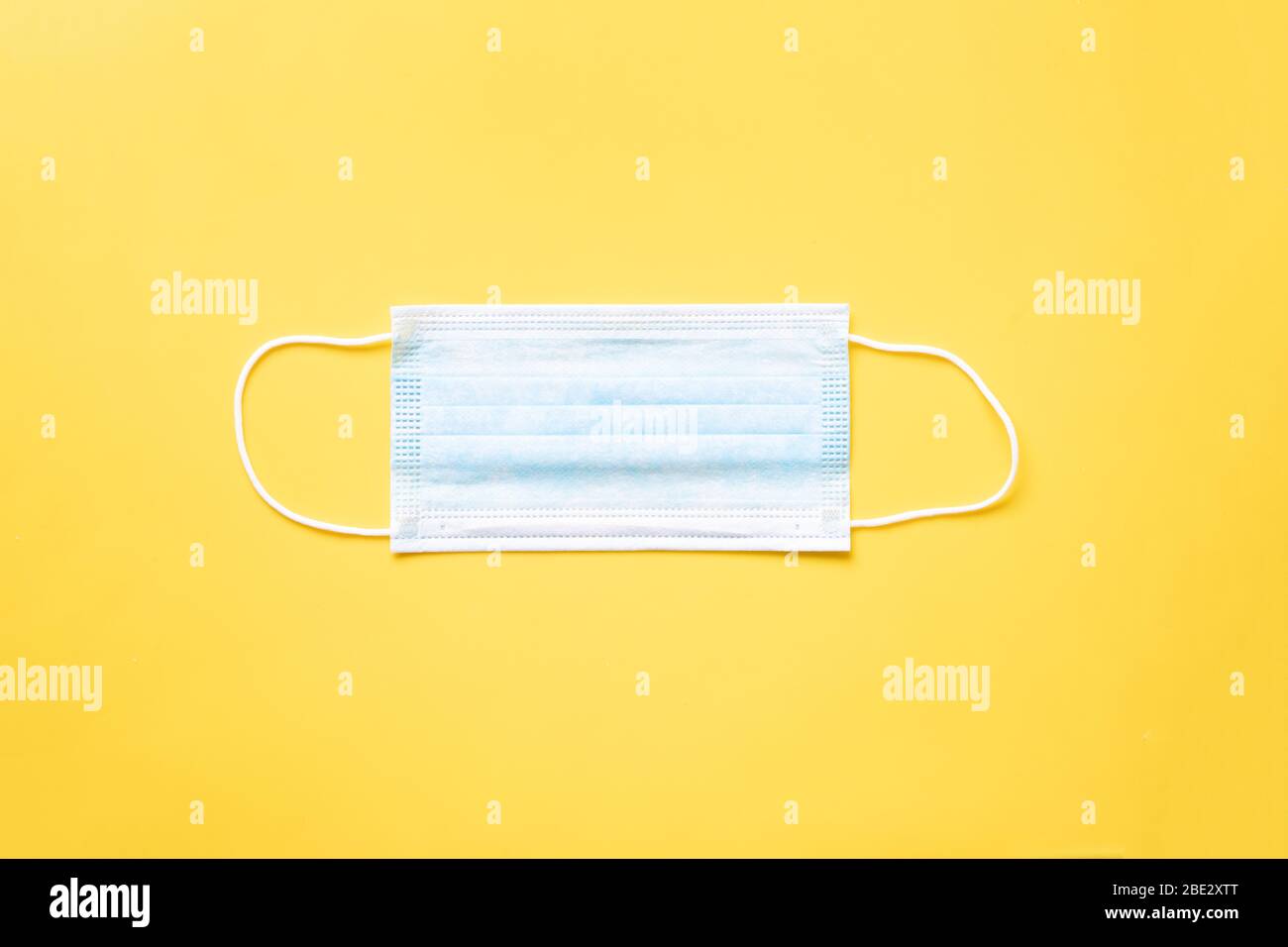a disposable surgical mask, layed flat on yellow background Stock Photo