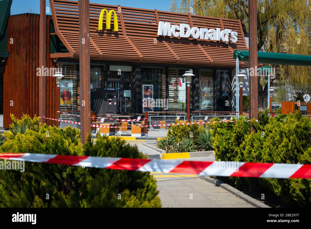 Red and white striped tape at the closed for normal business McDonald's fast food restaurant allowing only drive-in or drive-thru takeaway food due to the spread of the Coronavirus Pandemic of Covid-19 in Sofia, Bulgaria as of April 2020 Stock Photo