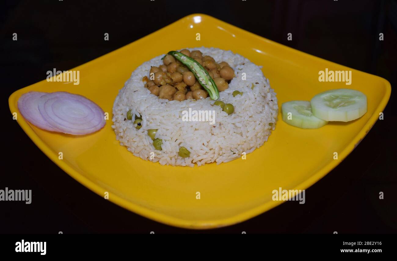 Delicious Indian traditional authentic Punjabi food Chawal Chole (rice with chickpea dish) with sliced onion, cucumber, lemon and green chilies Stock Photo