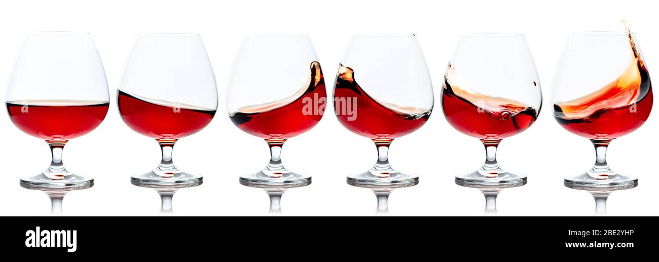 Set of brandy snifters with cognac splashes. Splashes of cognac in glasses, isolated on white