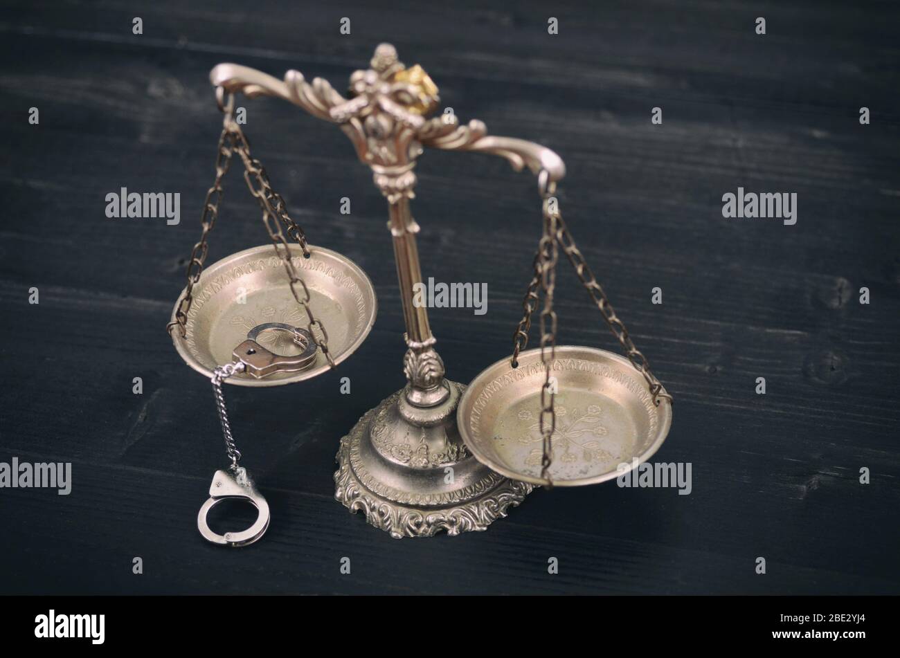 Law and Justice, Legality concept, Scales of Justice and handcuffs on a black wooden background. Stock Photo