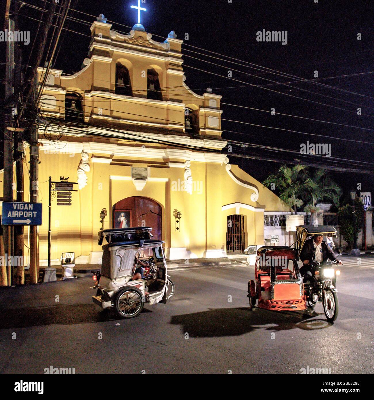 Tuk tuk, motorbike or tricyle riding in Vigan at nightime in front of a church Stock Photo