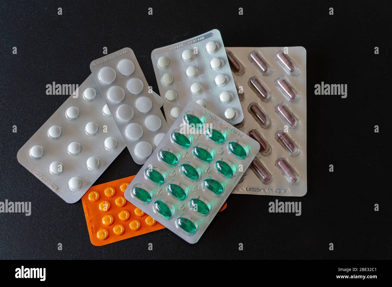 A lot of coloured pills in blisters on black background. Healthcare and ...