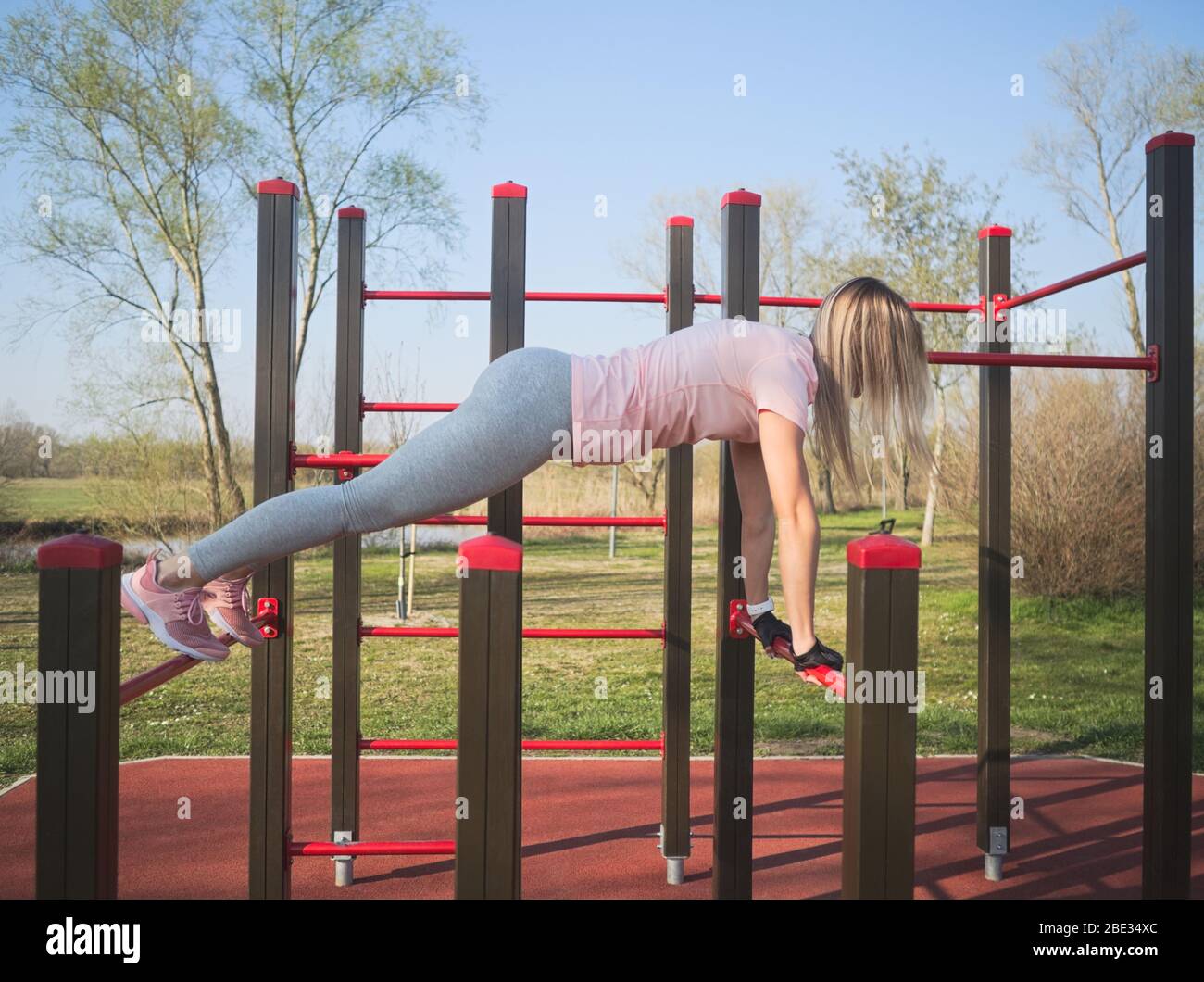 Young Athletic Woman Doing Push Ups on Monkey Bars in the Park Stock Photo