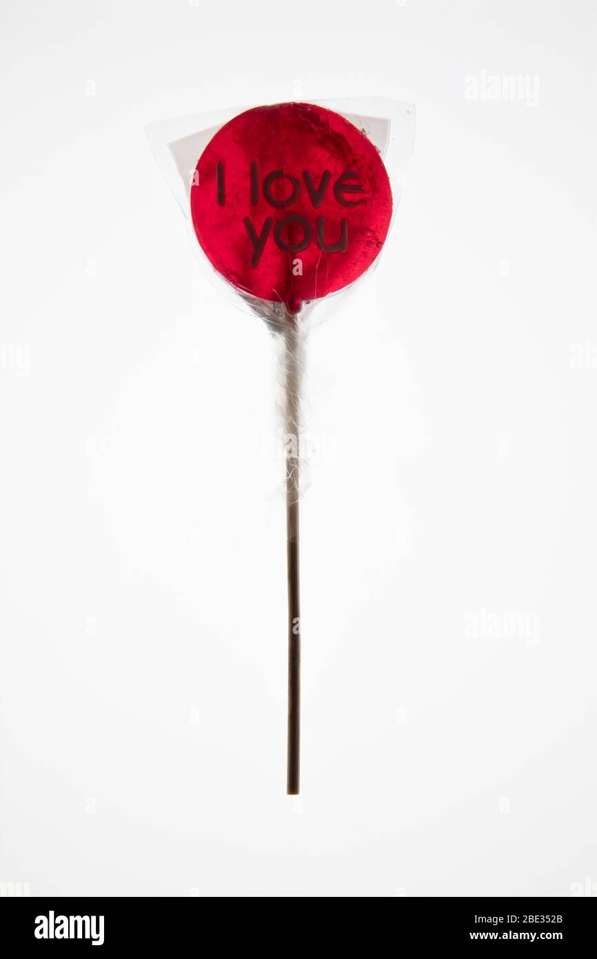 a sweet wrapped 'I Love you' red transparent lollypop against a bright white background, flat lay, top view Stock Photo