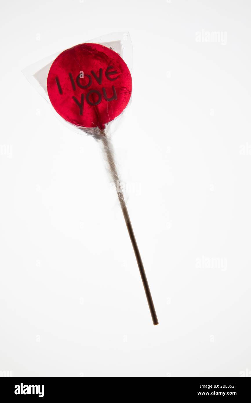 a sweet wrapped 'I Love you' red transparent lollypop against a bright white background, flat lay, top view Stock Photo