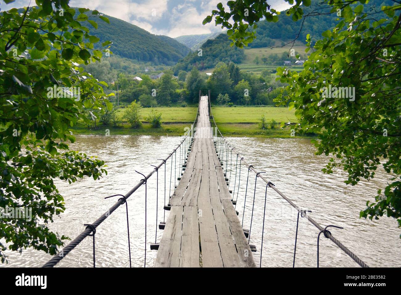 Suspension bridge over the river in the mountains by a summer day Stock ...