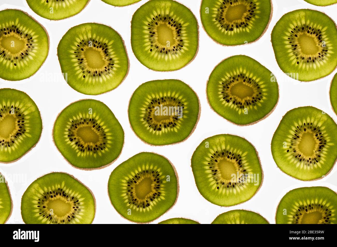 a beautiful image of an interesting pattern detail of kiwi fruit slices against a bright white background, flatlay Stock Photo
