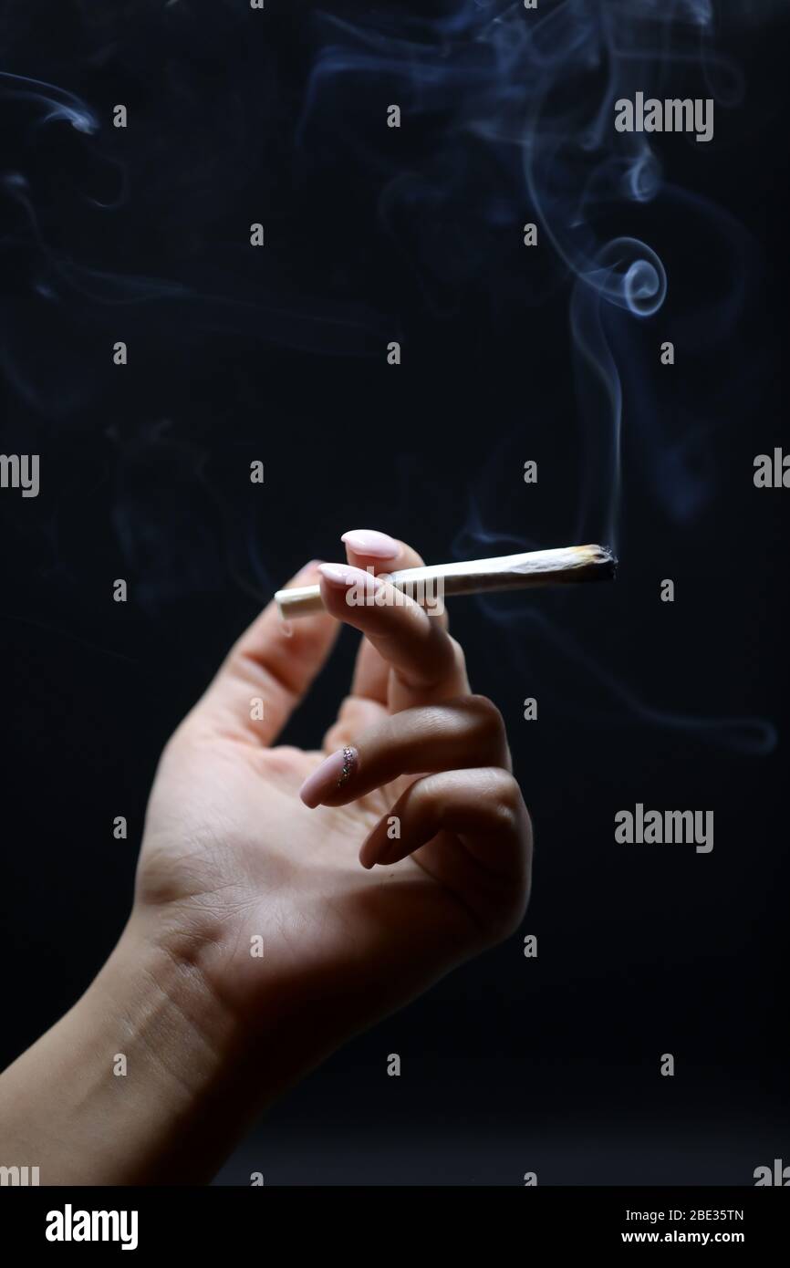woman hand holding cigarette Woman hand holding cigarette. Smoking cannabis joint. Medical use. Isolated  on a black background Stock Photo