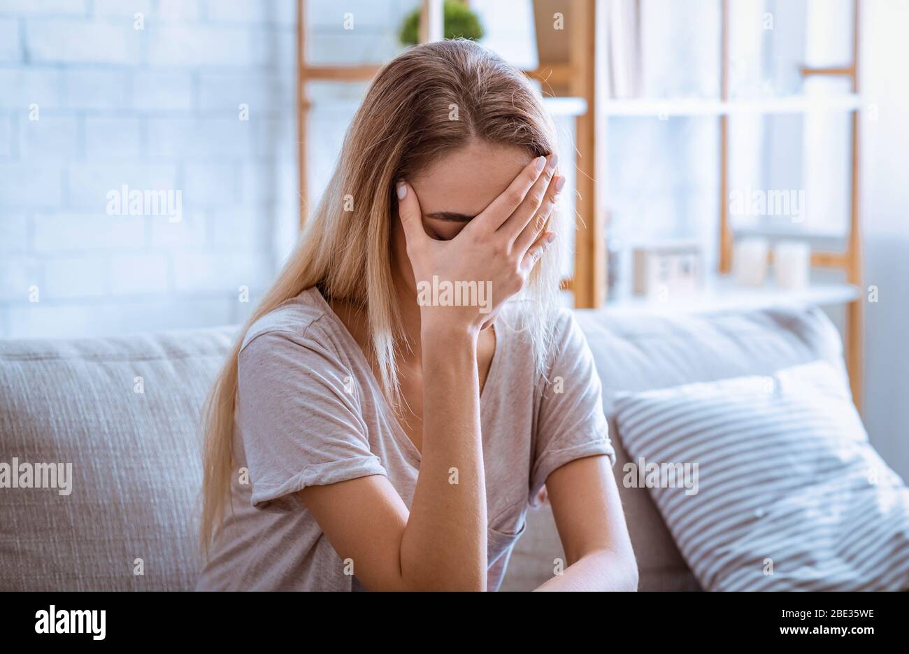 Sad woman covered face with hand. Stay alone at home Stock Photo