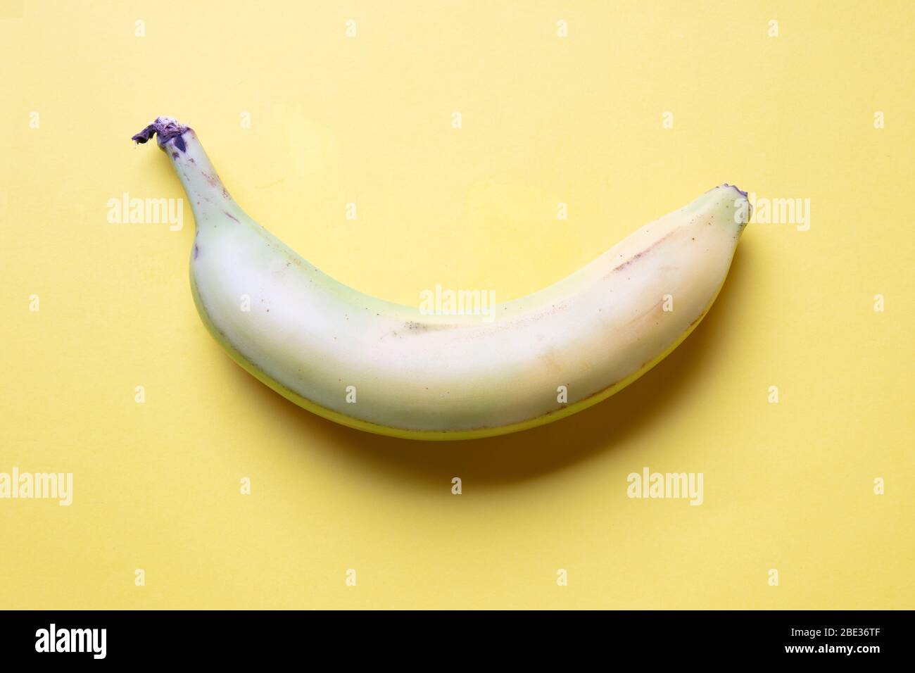 a fantastic pastel coloured image of a banana against a yellow background, flat lay, top view Stock Photo