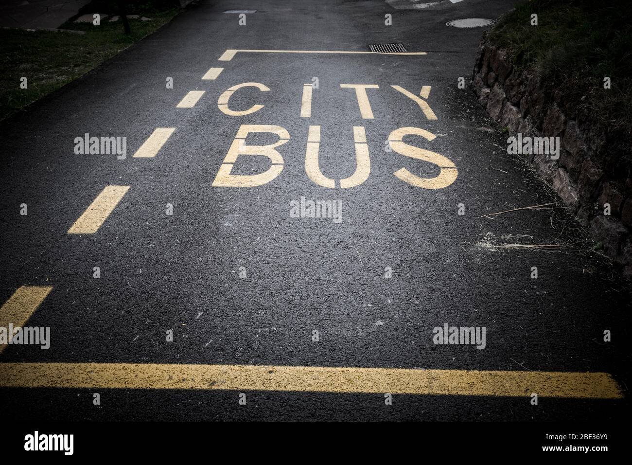 City Bus stop sign painted in yellow on a black tarmac road, Italy. Stock Photo