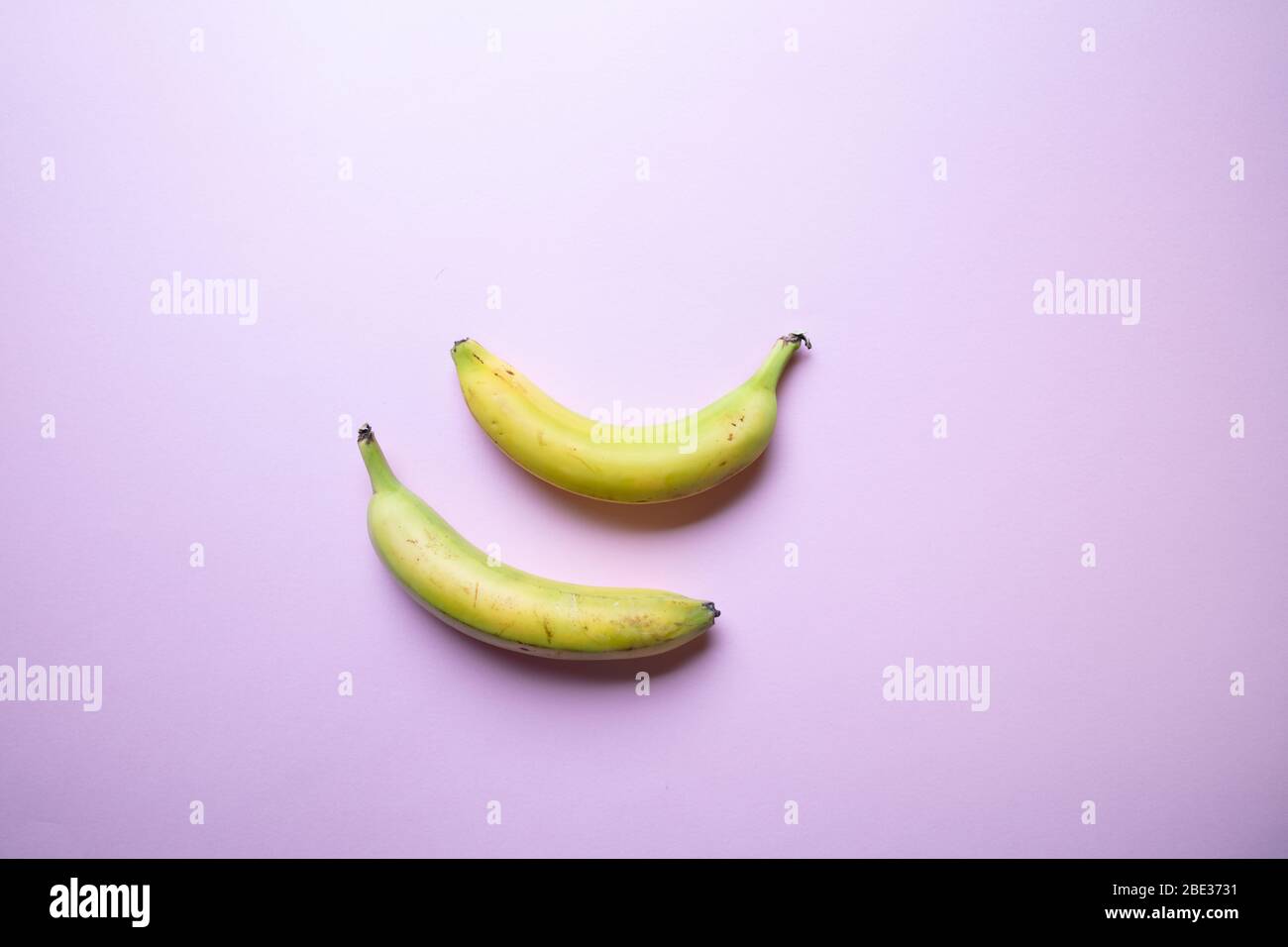 a stylish pastel coloured image of two bananas an a pink background, flat lay, top view Stock Photo