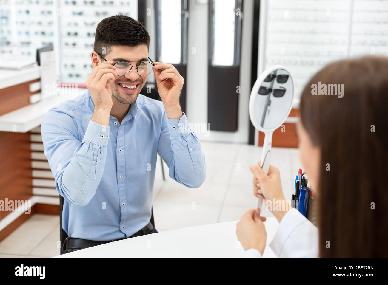 Optometrist helping guy to choose correction glasses Stock Photo