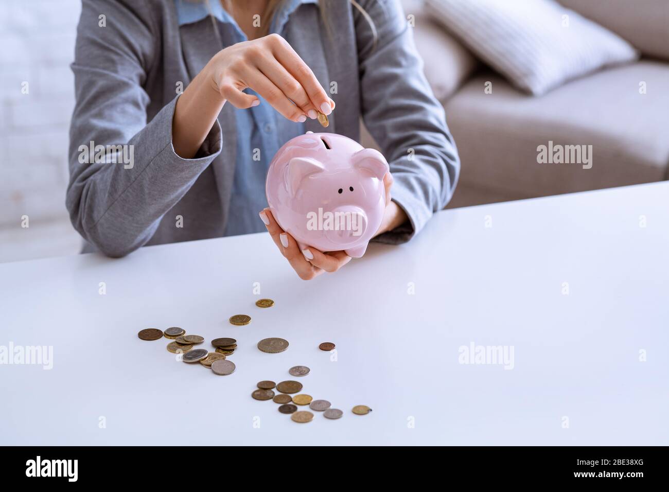 Reduce budget during quarantine. Woman puts coins in piggy bank Stock ...