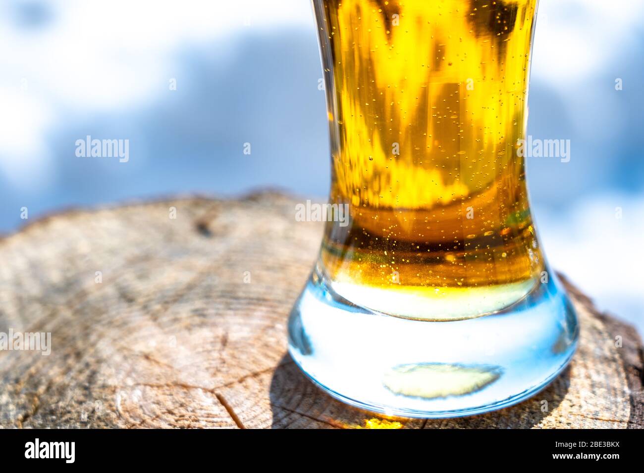 Light beer in a glass goblet on a picnic with snow background. Beer foam on the walls of a glass in the sunlight Stock Photo